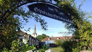A historic building with a church steeple, a sign reading "Gripsholmgårdshus & Celleriet," and white flowers in the foreground. - Gripsholms Värdshus (Mariefred)