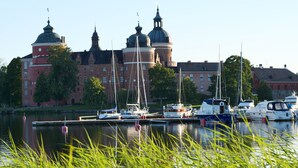 A marina with boats docked in front of a large building with domed roofs. - Gripsholms Värdshus (Mariefred)