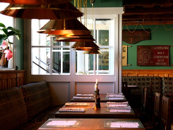 A restaurant interior with a wooden bench seating area, a table with menus, and a candle on the table.