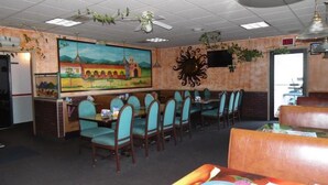 A restaurant with a mural, teal chairs, and a ceiling fan. - American Inn & Suites (Boone)
