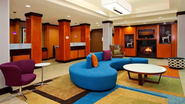 Un lobby moderno con un sofá azul, un sillón púrpura y una chimenea.