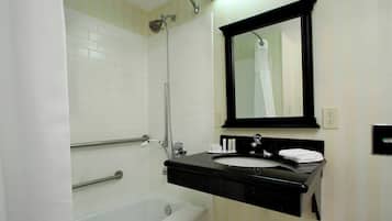A bathroom with a white bathtub, a black sink with a mirror above it, and a towel rack.