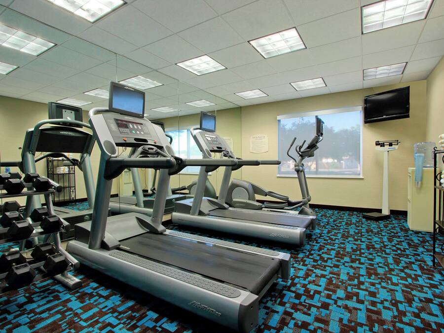 A fitness center with treadmills, a stair climber, and dumbbells.