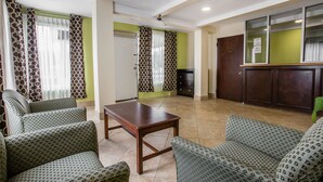 A hotel room with patterned green sofas, a wooden table, and a green wall. - Rodeway Inn Laurens (Laurens)