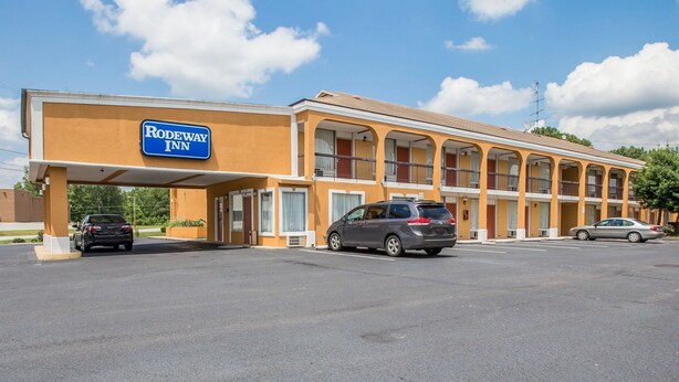 A motel with a sign reading "Rodeway Inn" and a parking lot with several cars.