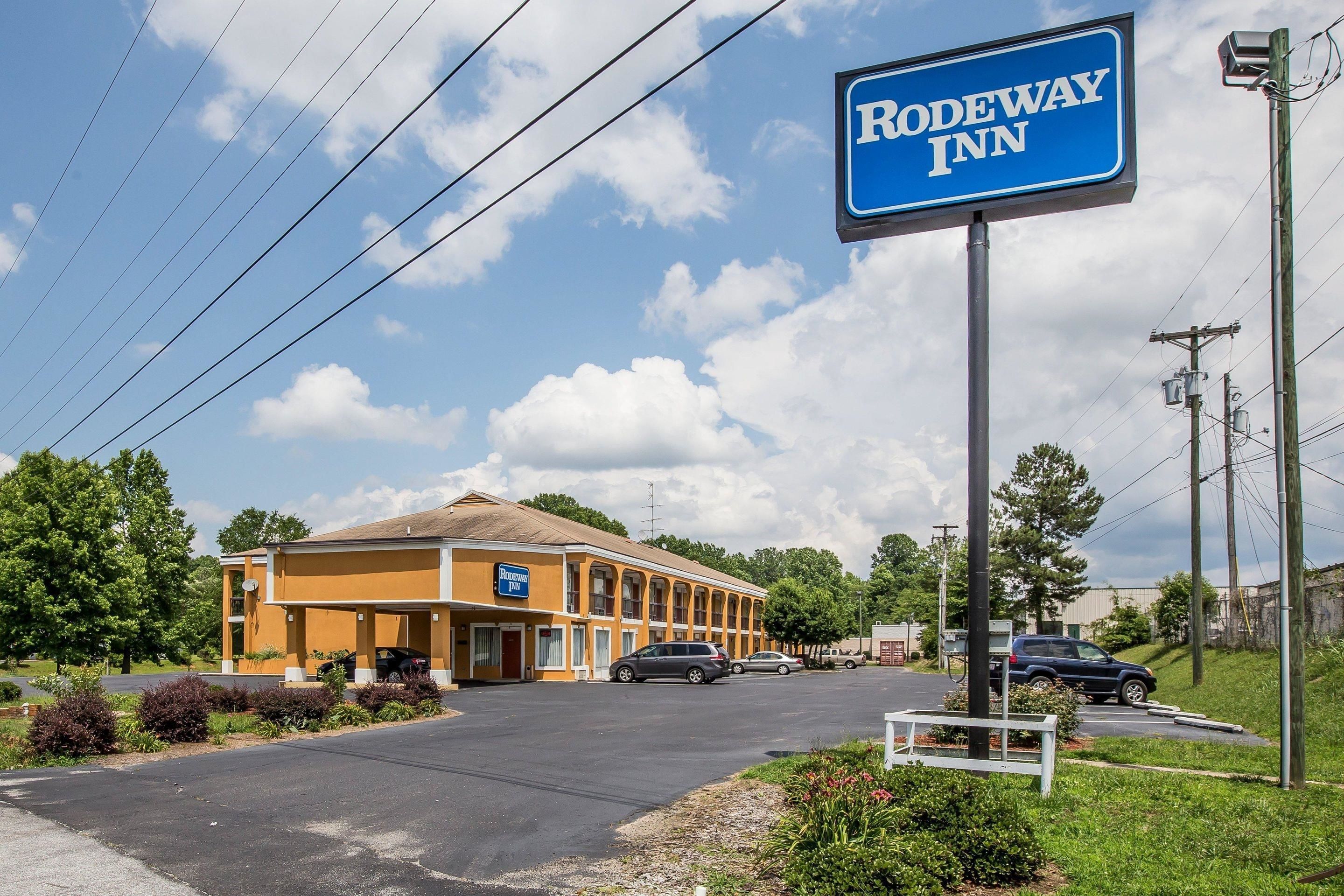 Un motel avec une enseigne indiquant « Rodeway Inn », composé d’un bâtiment à deux étages doté d’un toit plat et d’un parking situé à l’avant.