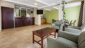 A hotel lobby with a reception desk, seating area, and a television. - Rodeway Inn Laurens (Laurens)