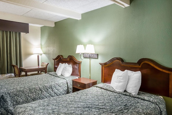 Habitación de hotel con dos camas, un escritorio y dos lámparas.