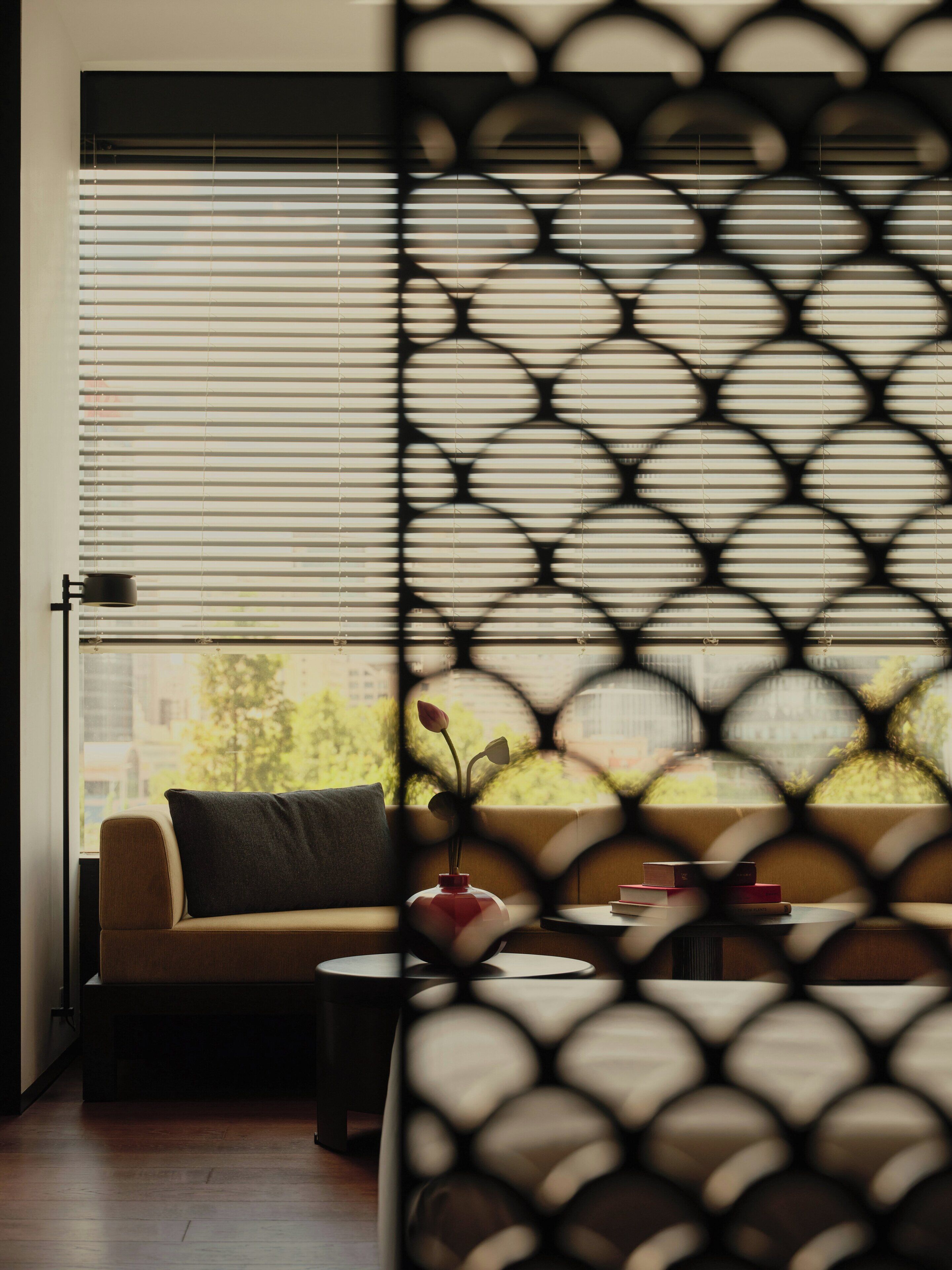 A room with a sofa, a small table, and a window with blinds.