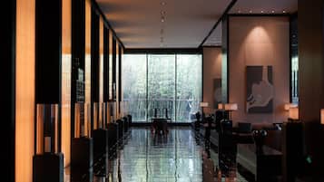 A modern hotel lobby with a reflective floor, large windows, and a reception desk.