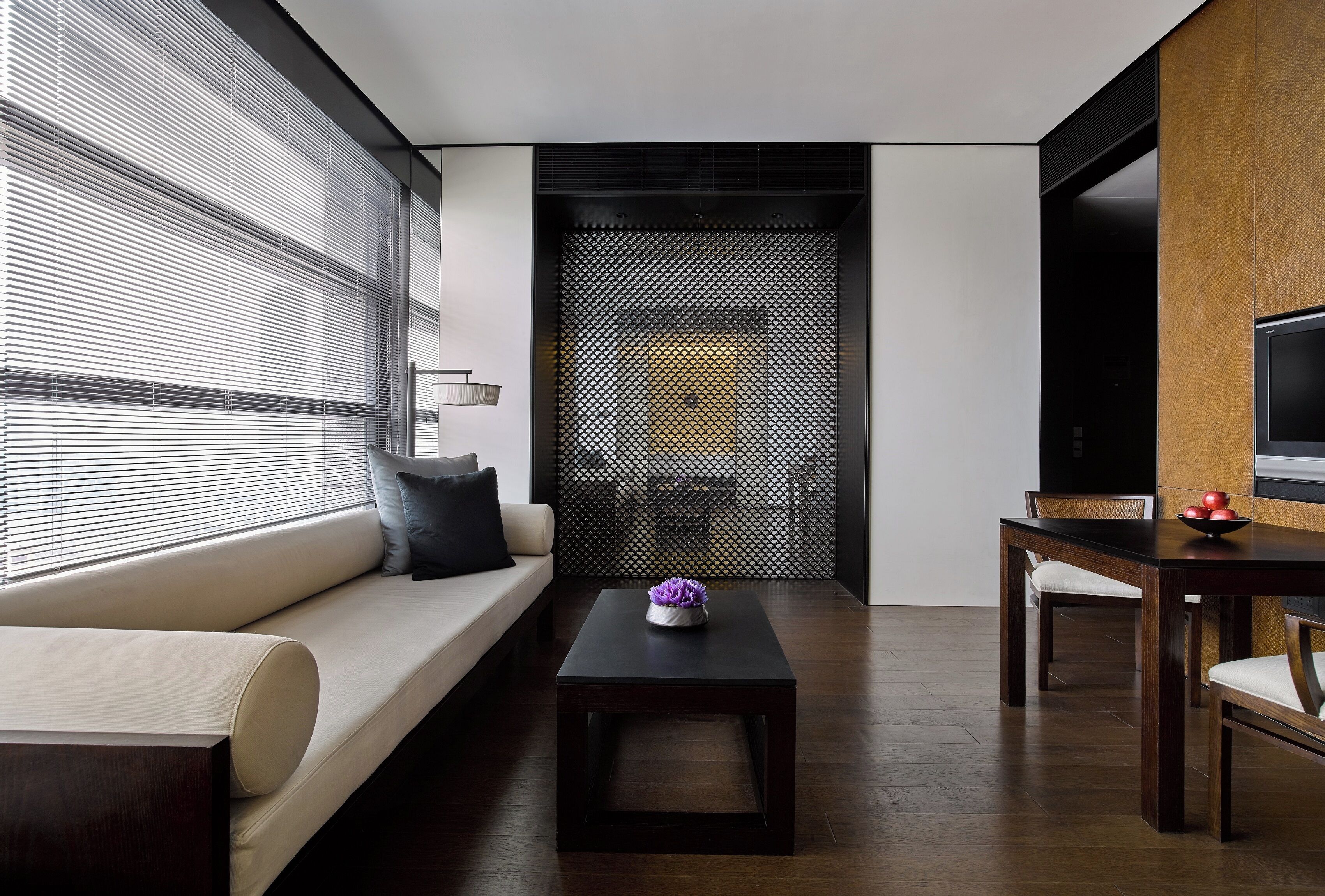 A modern living room with a sofa, a coffee table, a dining table, and a TV.