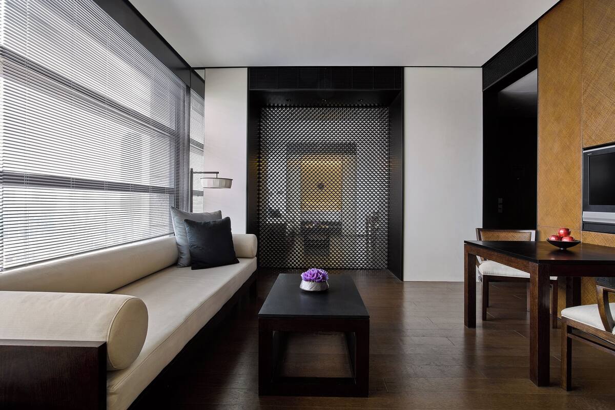 A modern living room with a sofa, a coffee table, a dining table, and a TV.