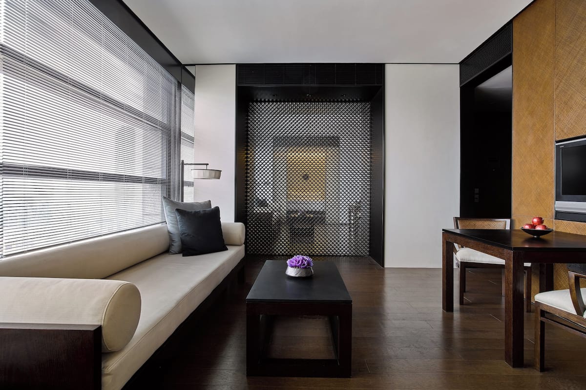 A modern living room with a sofa, a coffee table, a dining table, and a TV.