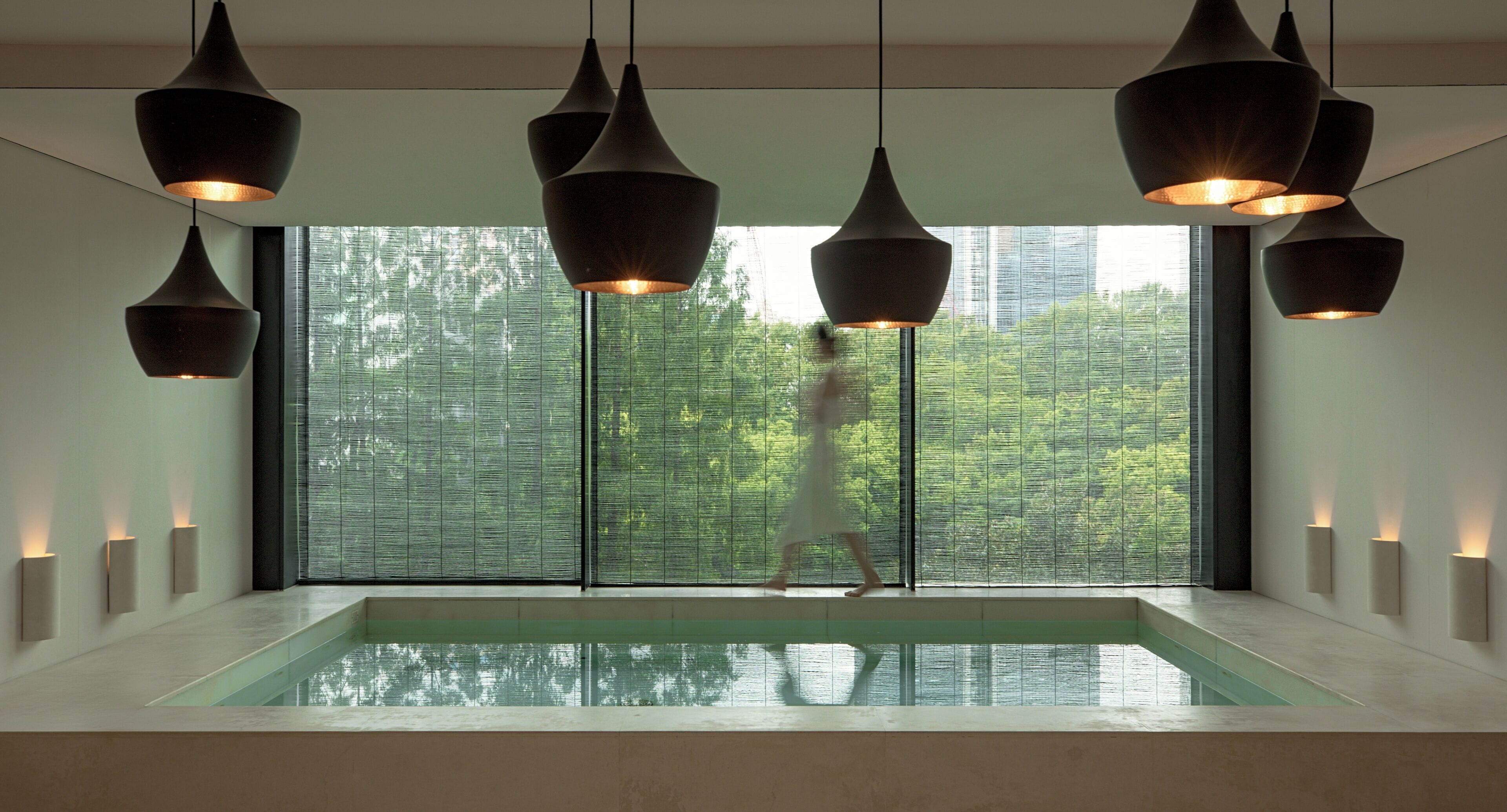 A modern interior with a large window, a pool, and pendant lighting.