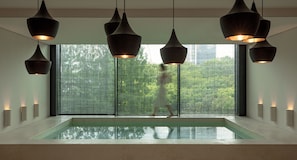 A modern interior with a large window, a pool, and pendant lighting.