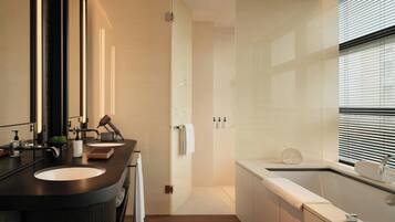 A modern bathroom with a double sink vanity, a large mirror, a towel rack, and a bathtub.