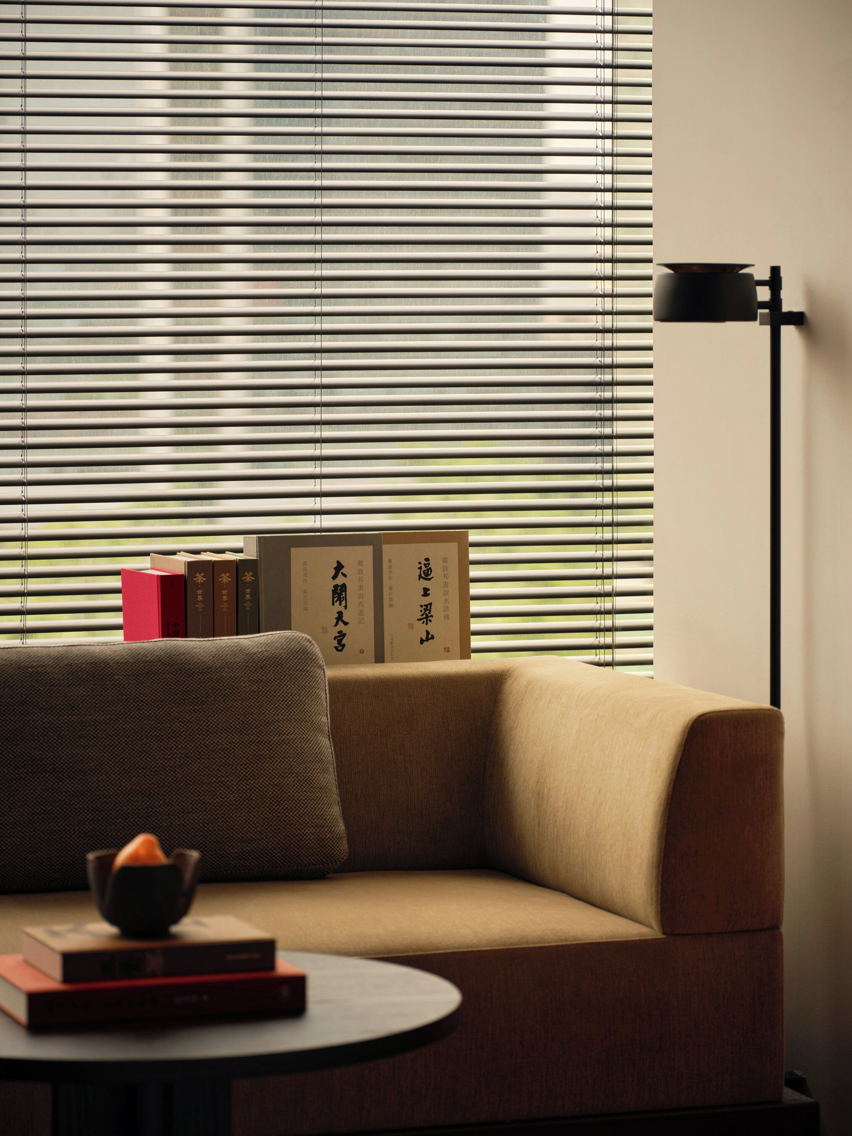 A modern living room with a sofa, a small table with books, and a floor lamp.