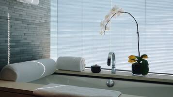 A bathroom with a sink, towel, and orchid plant.