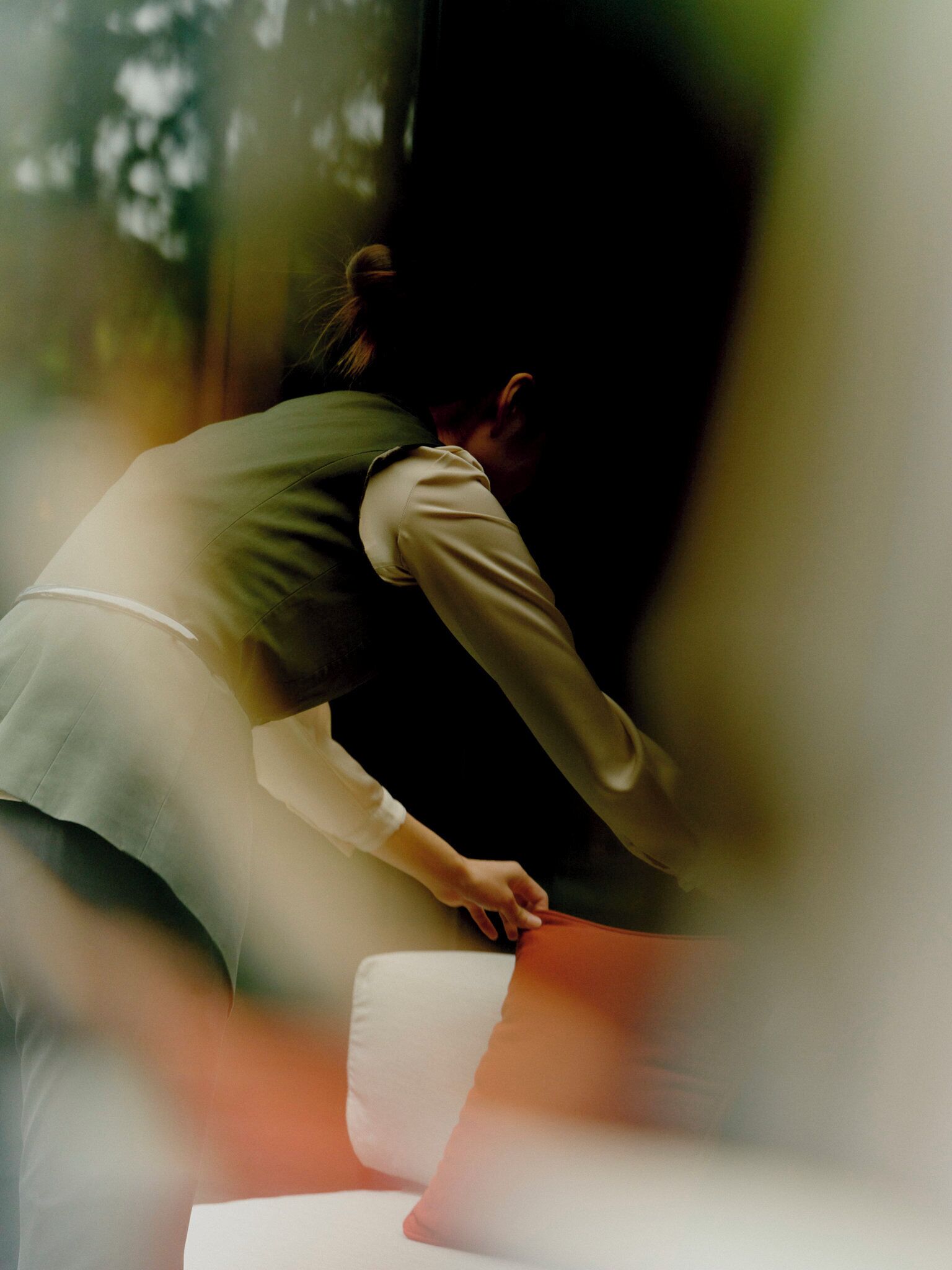 A person sitting on a bench in a shaded area.