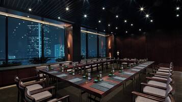 A conference room with a long table, chairs, and a city view through large windows.