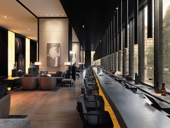 A modern hotel lobby with a long reception desk, seating area, and large windows offering views of the outdoors. -  The PuLi Shanghai  (Shanghai)
