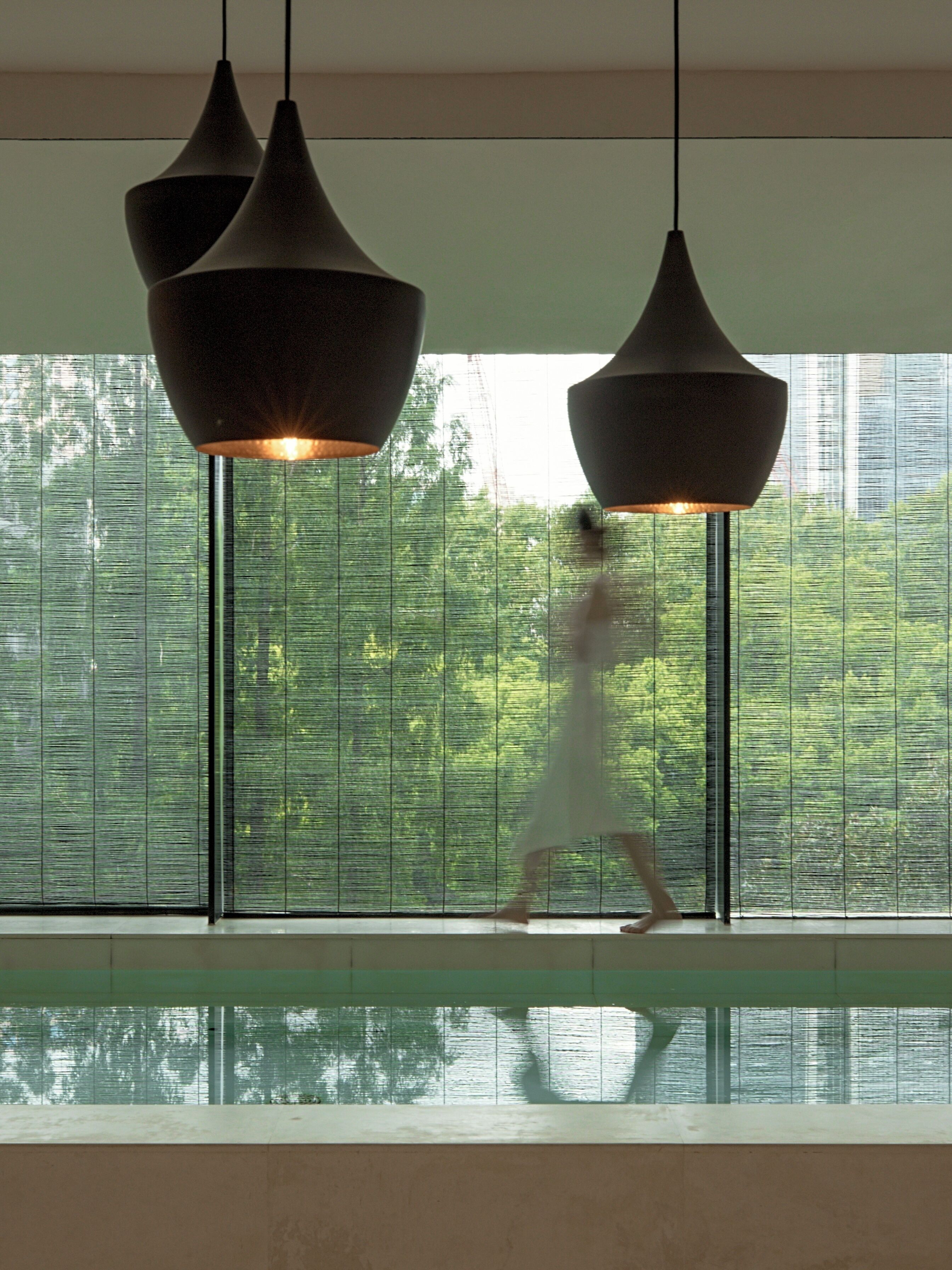 A modern interior with a large window, a pool, and pendant lighting.