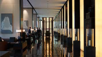 Un moderno vestíbulo de hotel con piso reflectante, zonas de estar y obras de arte en las paredes.