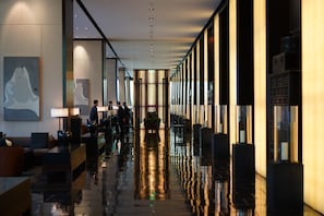 A modern hotel lobby with a reflective floor, seating areas, and artwork on the walls. -  The PuLi Shanghai  (Shanghai)