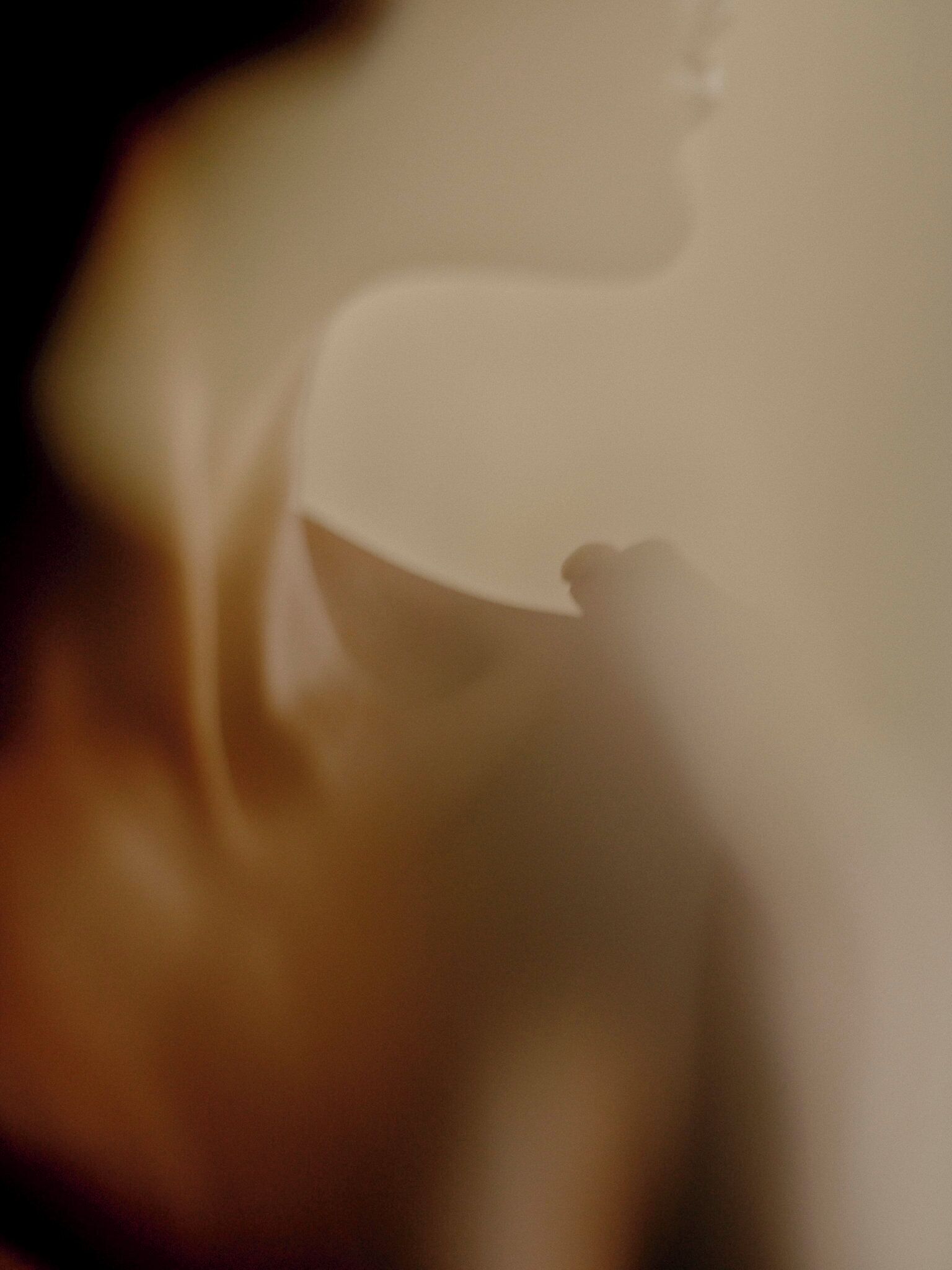 A blurred interior view of a room with a white ceiling and a visible light fixture.