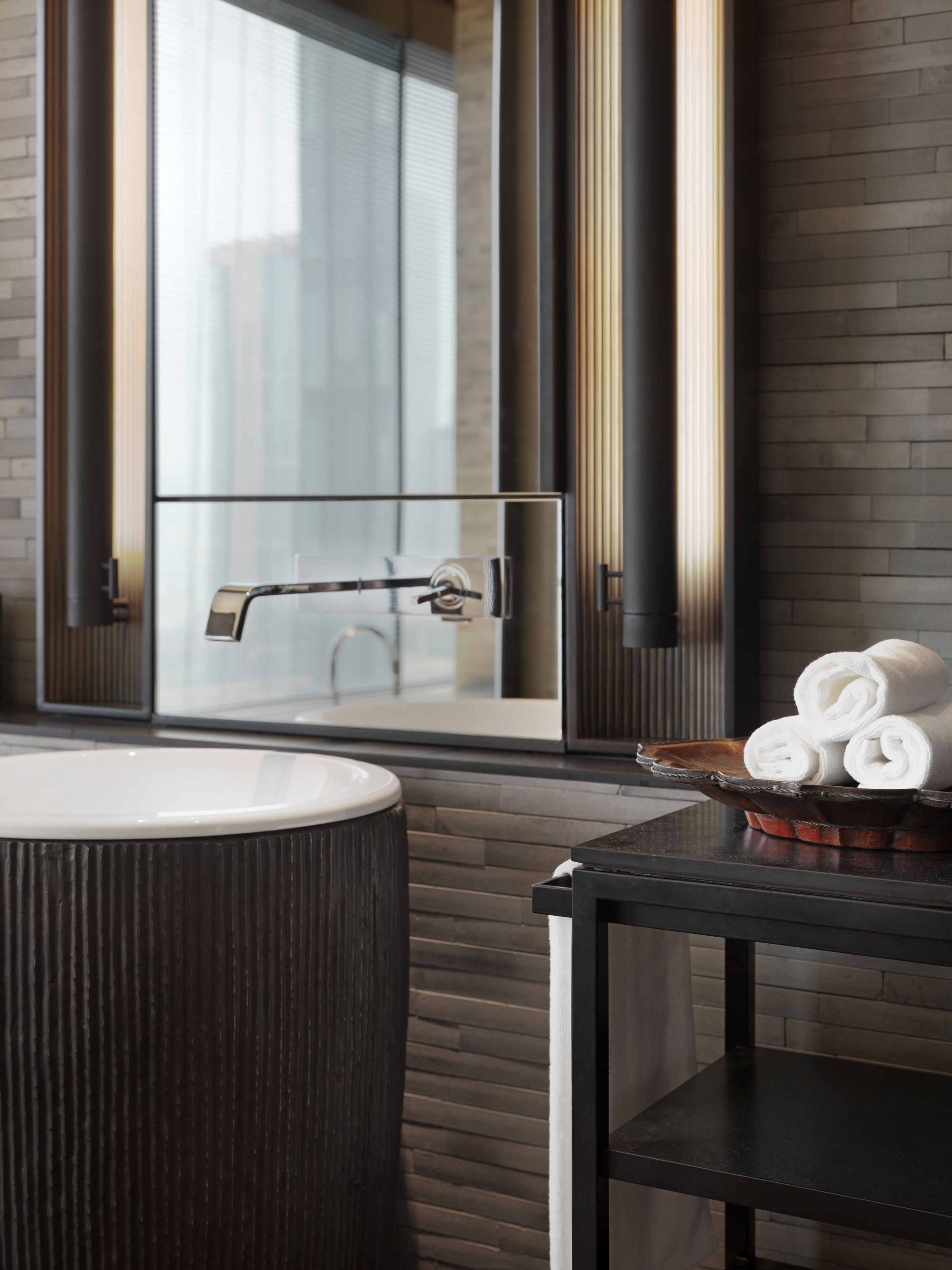 A modern bathroom with a large bathtub, a glass-enclosed shower, and a wooden vanity with towels.
