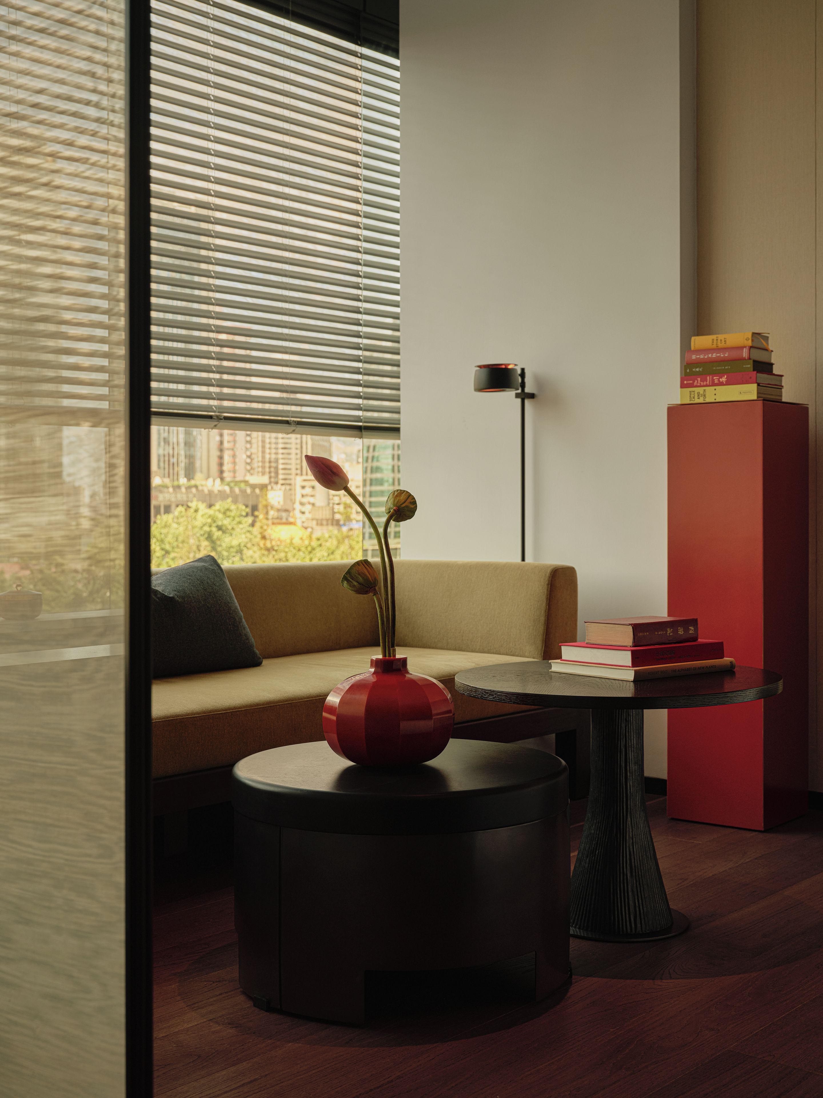 A modern interior with a sofa, a round table with a vase, and a bookshelf.