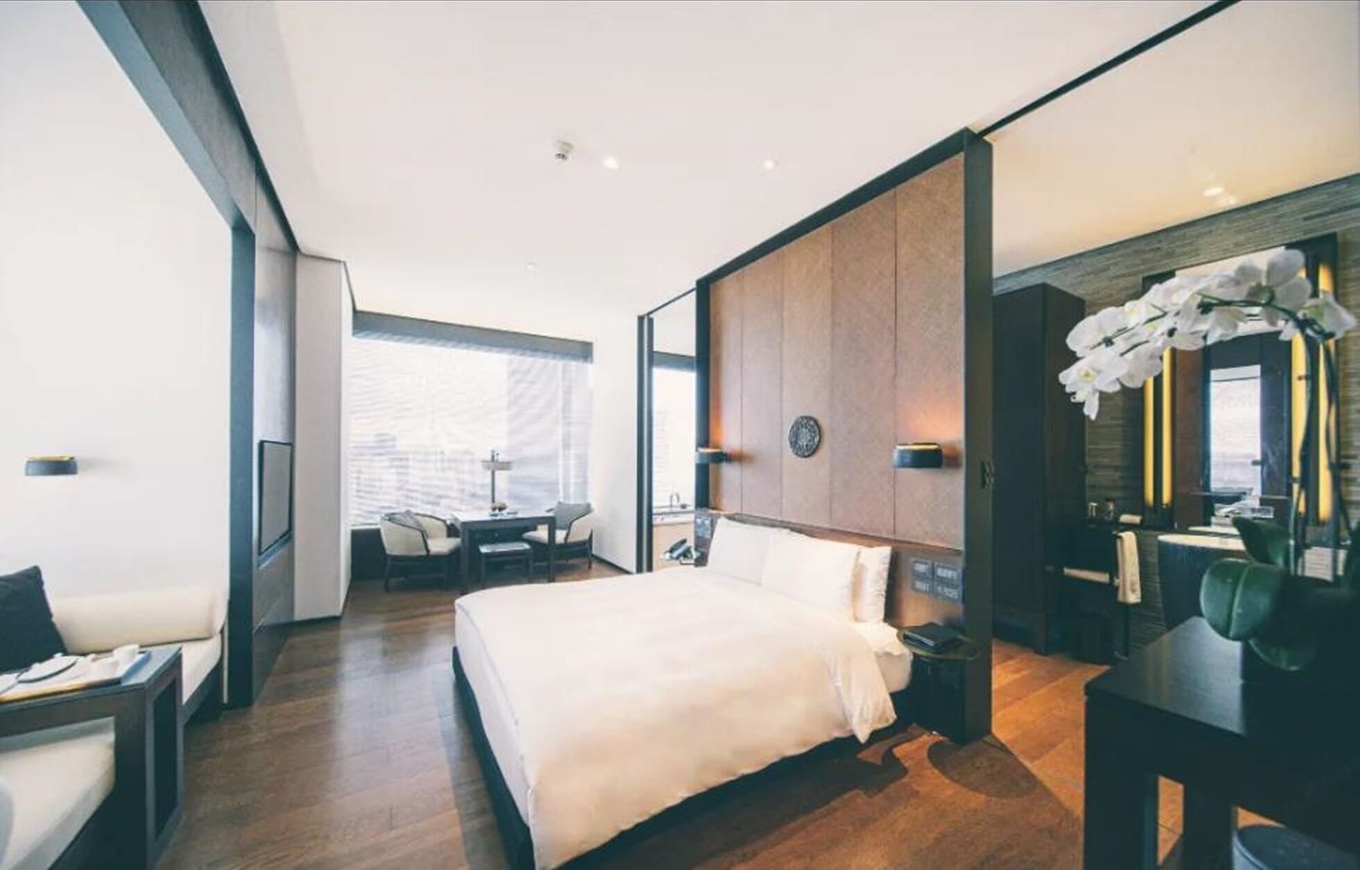Una habitación de hotel moderna con una cama grande, un escritorio y una zona de estar con sillas.