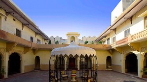 A courtyard with a central gazebo, surrounded by arches and a tiled floor. - Fort Khejarla, Jodhpur (Bilara)