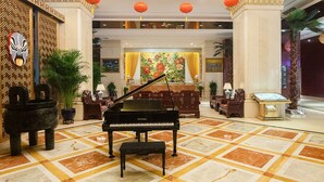 Un amplio vestíbulo con un piano de cola, decoraciones ornamentales en las paredes y un suelo con diseños.