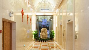 Un vestíbulo de hotel con piso de mármol, un candelabro y una estatua.