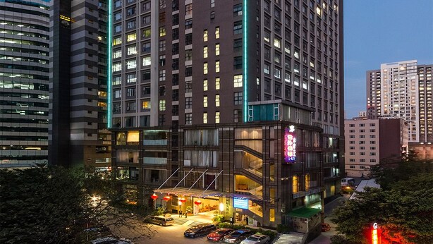 Un hotel de varios pisos con un diseño moderno, que cuenta con una entrada destacada con zona cubierta y señalización visible.