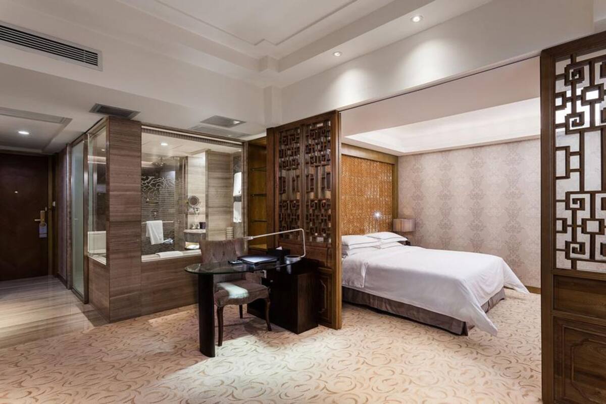 A hotel room with a desk, a bed, and a bathroom.