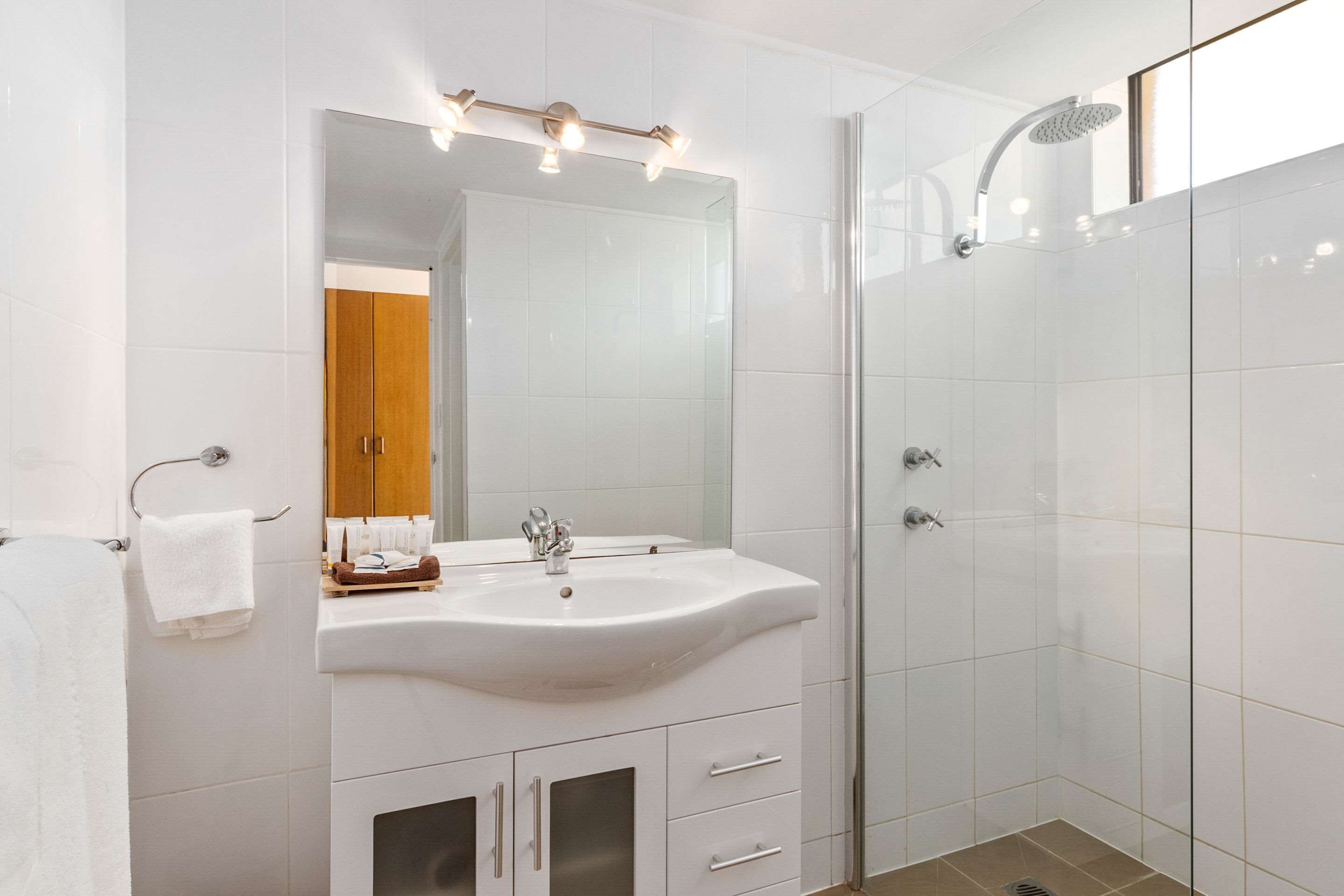 A modern bathroom with a white sink, mirror, and shower.
