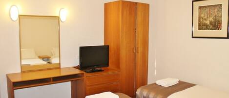 Habitación de hotel con un escritorio de madera, televisión, dos camas y un cuadro en la pared.