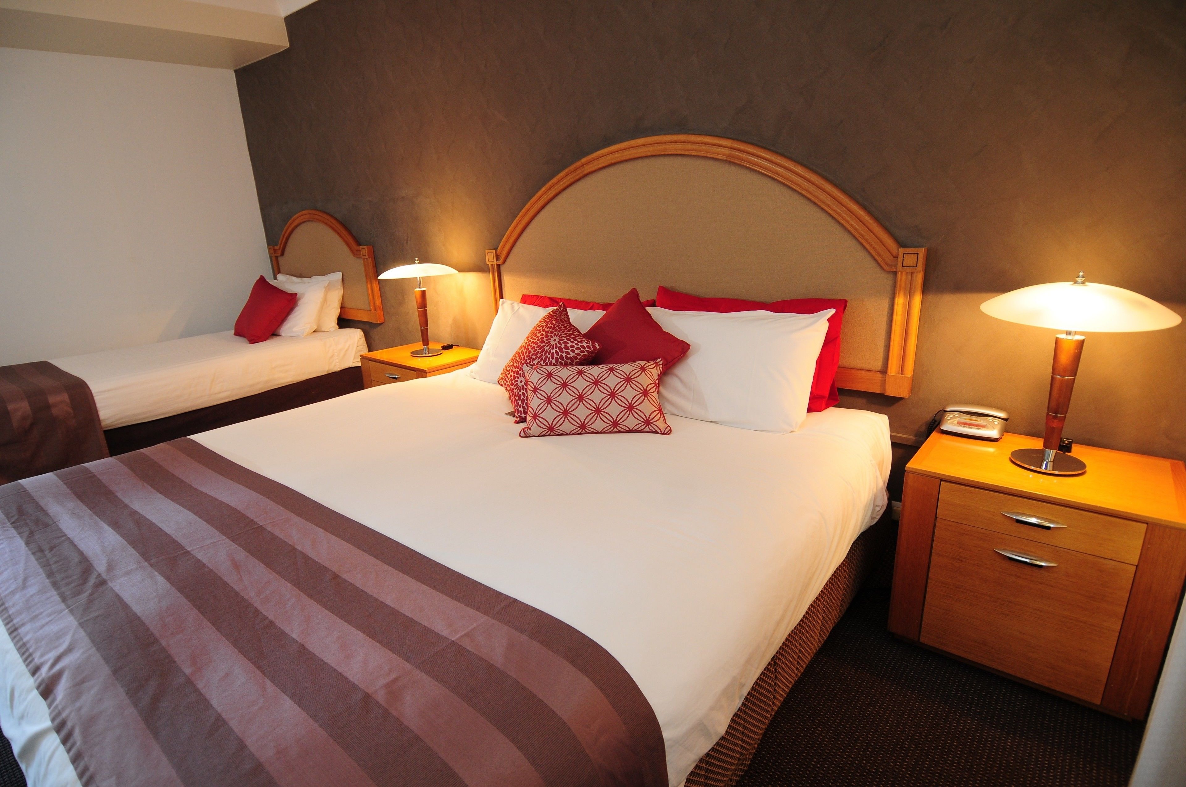A hotel room with a large bed, two bedside tables, a nightstand, and a mirror.