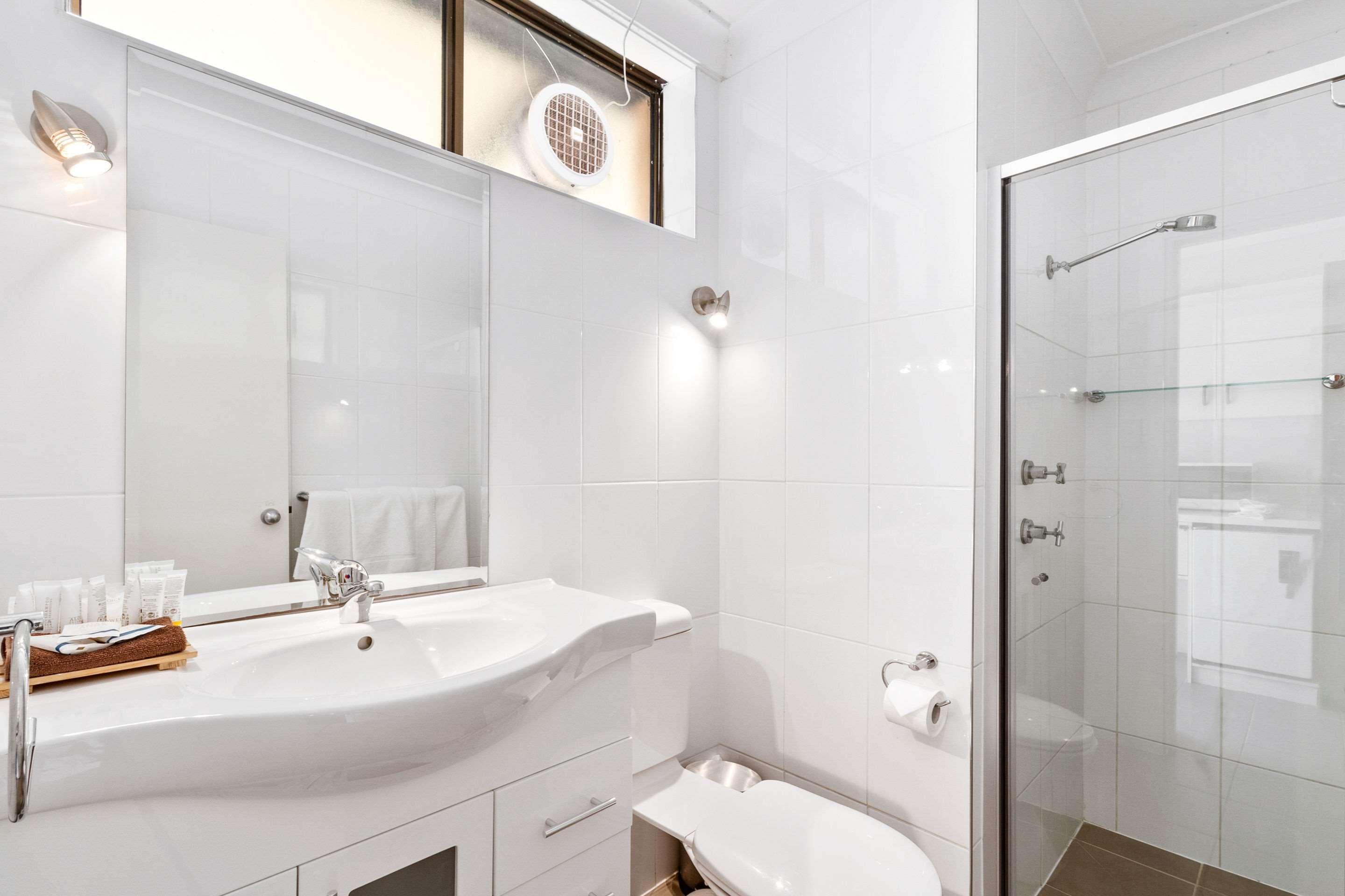 Une salle de bain moderne avec un grand lavabo, un miroir et une douche à parois de verre.