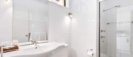 Une salle de bain moderne avec un grand lavabo, un miroir et une douche à parois de verre.
