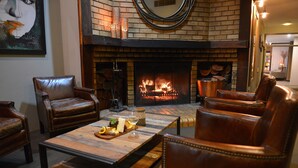 Una sala de estar acogedora con sillones de cuero, una mesa de centro de madera con aperitivos y una chimenea.