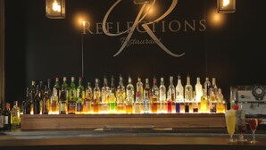 Un bar con una variedad de botellas de licor y copas, iluminado por luces colgantes.