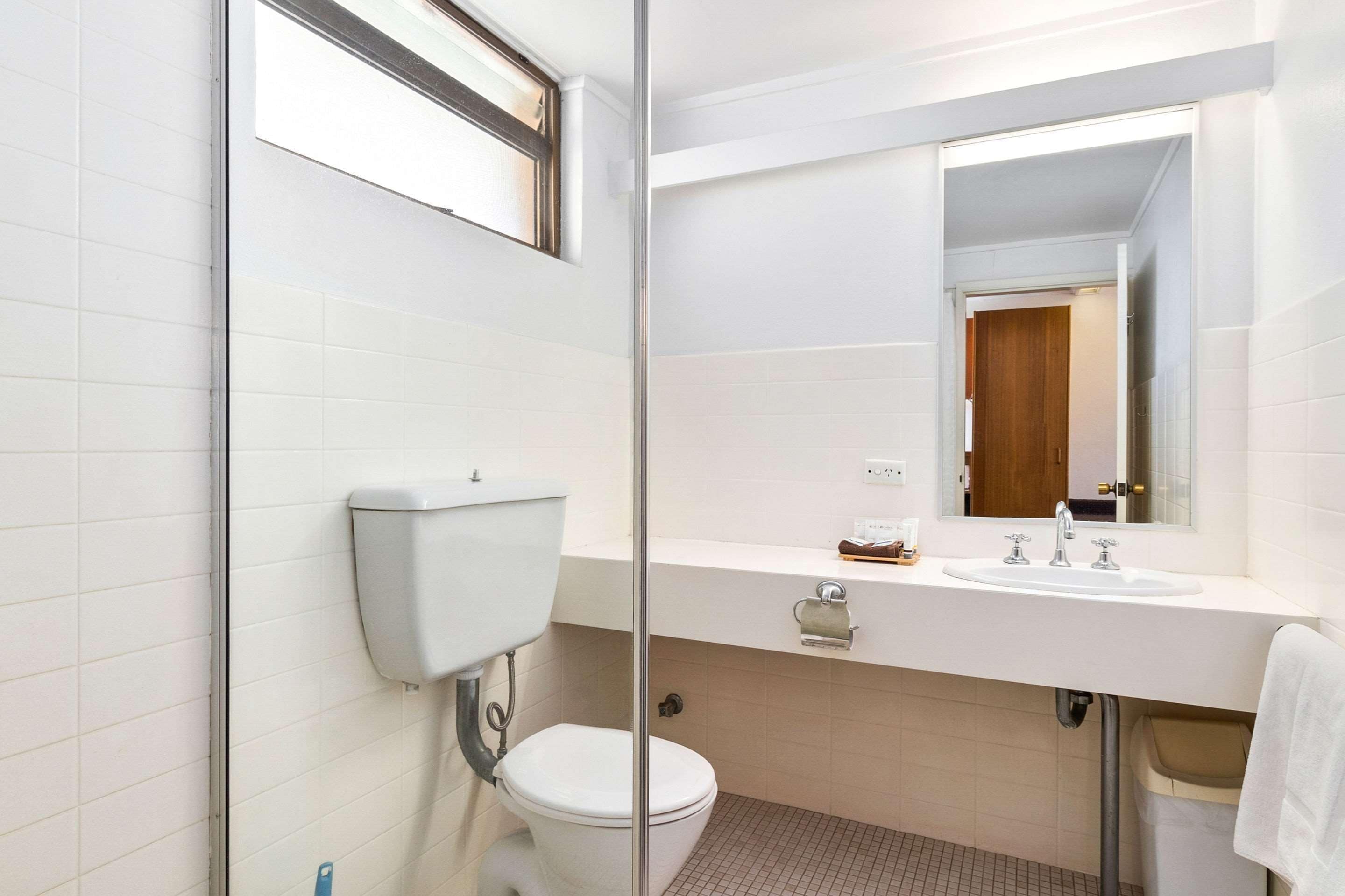 Une salle de bain avec des toilettes, un lavabo et un miroir.