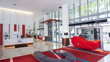 Un hall d’entrée moderne avec un comptoir d’accueil, un espace salon et de grandes fenêtres.
