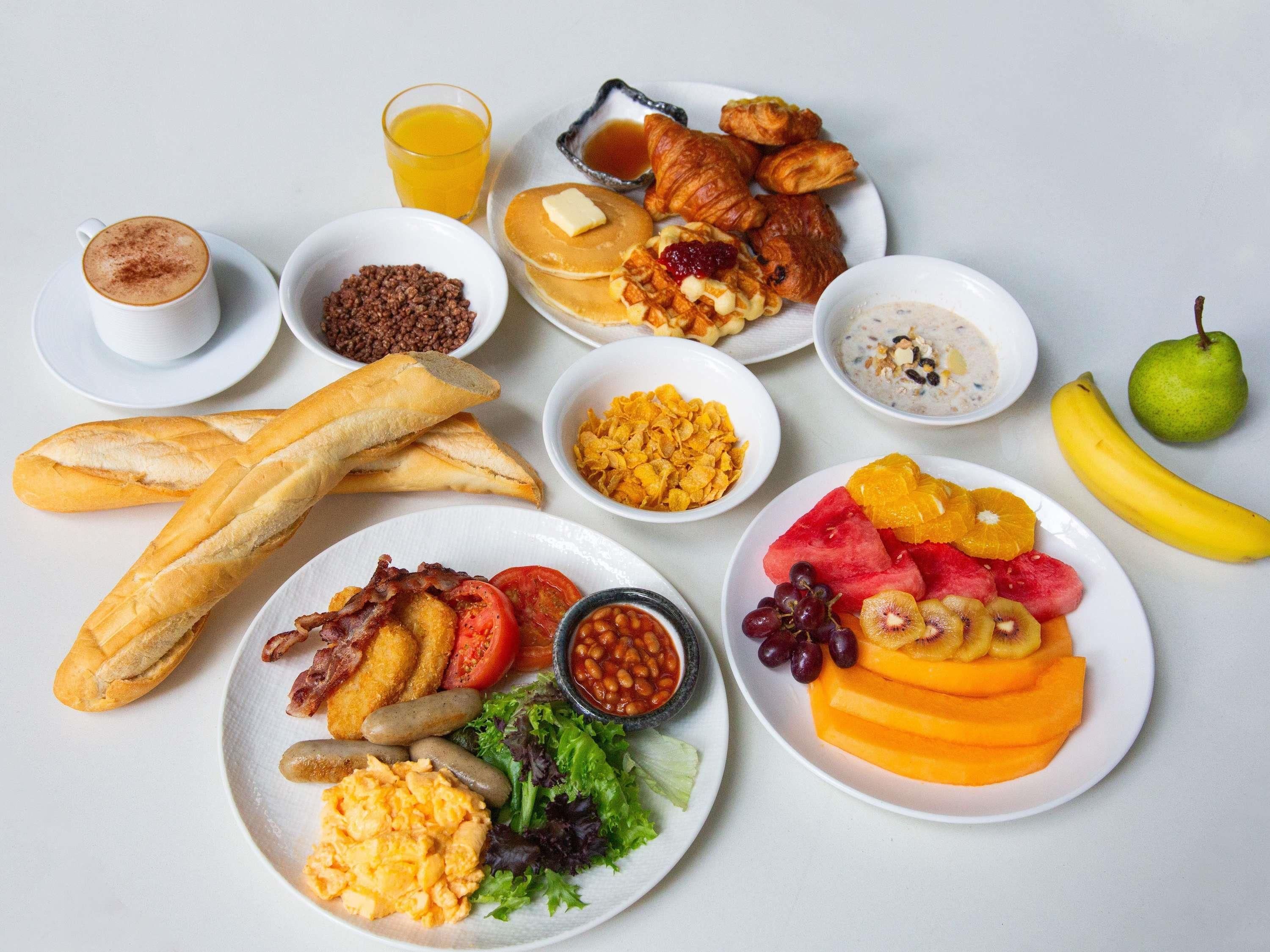 Una mesa con una variedad de platillos y frutas para el desayuno.