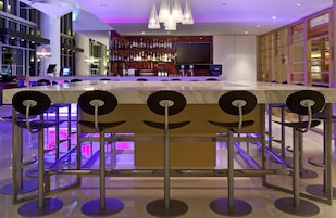 A bar area with a marble counter, multiple bar stools, and a television screen.