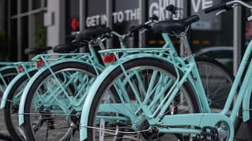 A row of turquoise bicycles parked in front of a building with a sign that reads 'Get in to the GRIOVE.'