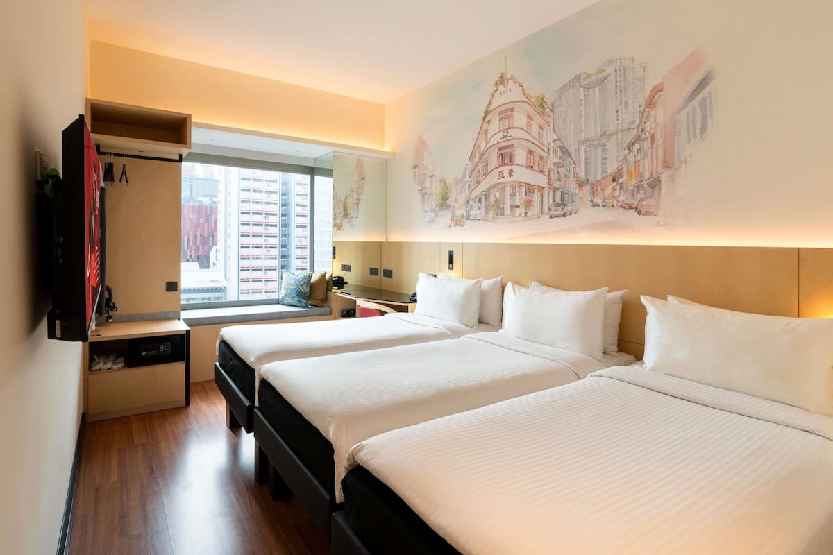 Habitación de hotel con dos camas, un televisor, un escritorio y un ventanal grande.